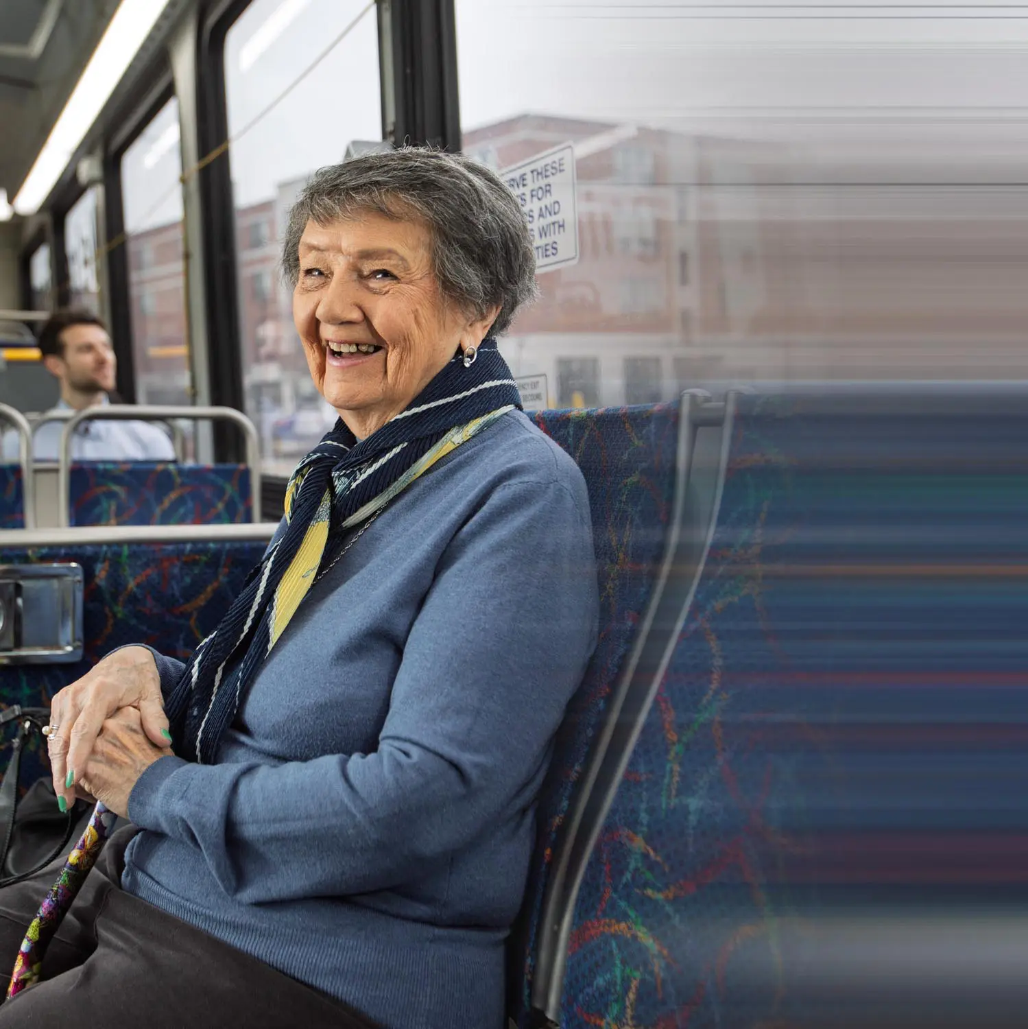 Person sitting in courtesy seating area on bus.