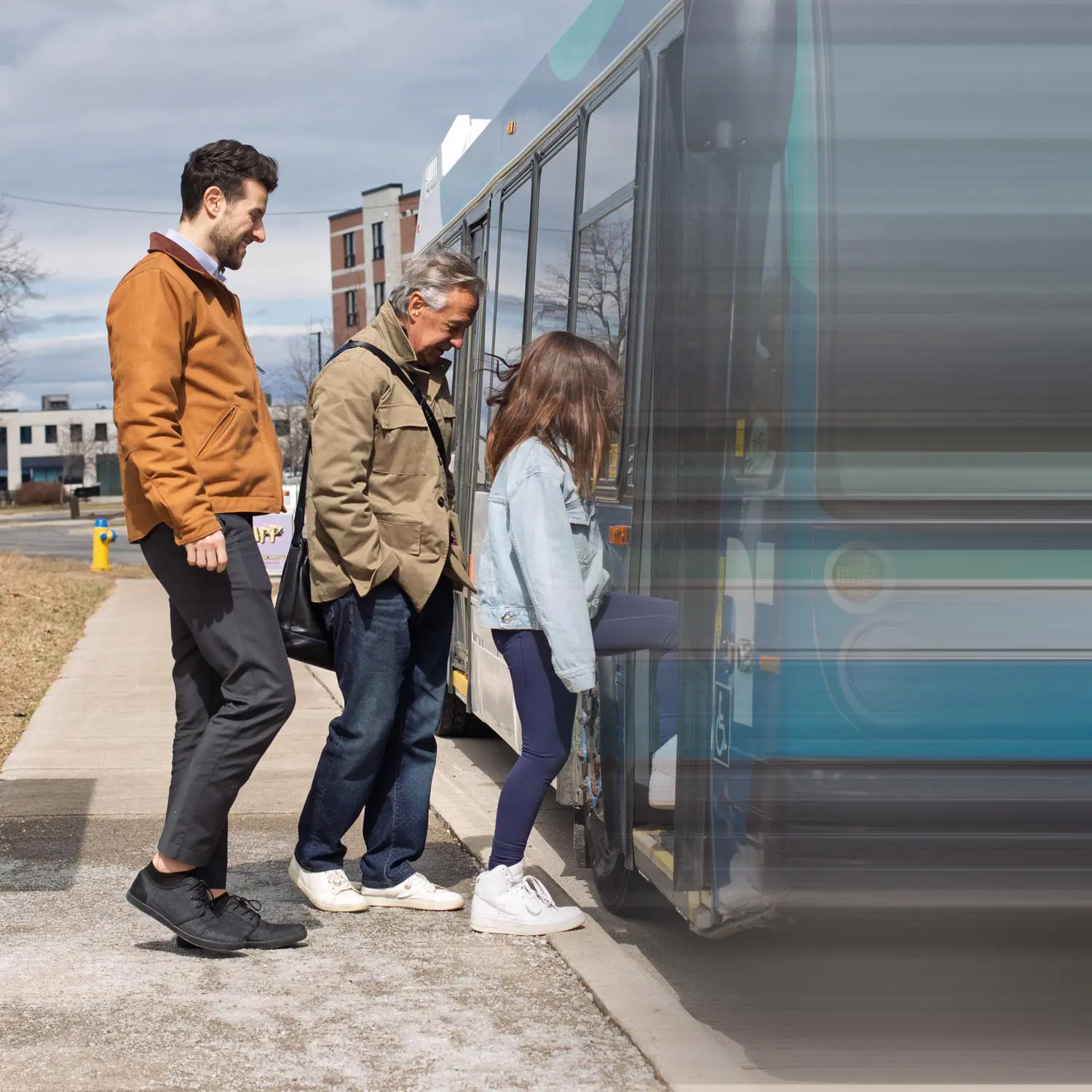 Three people boarding a city bus, with a young woman stepping onto the bus and two men waiting behind her on the sidewalk.